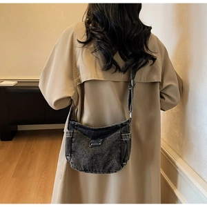 Vue détaillée du tissu denim délavé avec poches latérales et bandoulière réglable sur le sac