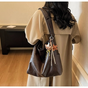 Detail of deep brown faux leather tote with vintage texture and cute charms