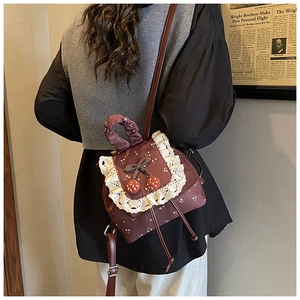 Détail d'un mini sac à dos vintage marron avec dentelle blanche et décor de cerise
