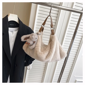 Dettaglio borsa a spalla in peluche bianco sporco con tracolla marrone e ciondolo a coniglio