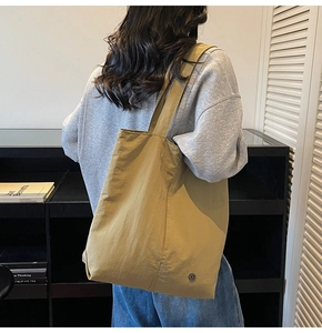 Vue arrière du mannequin portant un grand sac cabas en nylon imperméable de couleur kaki