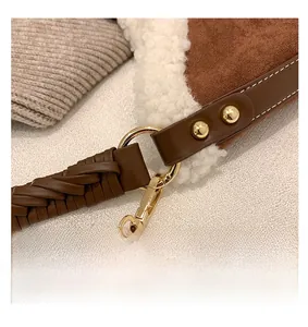 Detail of golden metal hook on woven leather strap with faux shearling bag trim