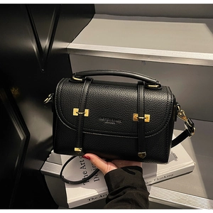 Close-up of black lychee grain leather bag with gold hardware and embossed fashion logo