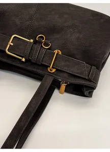 Close-up of vintage leather handbag featuring gold buckle detail and textured finish
