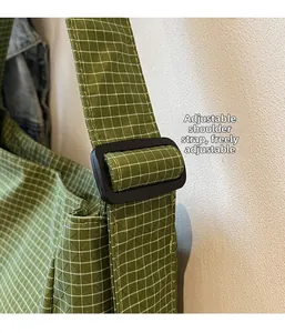 Detail of adjustable shoulder strap buckle on green plaid oxford cloth tote bag