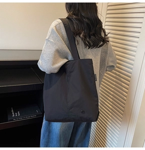 Vue détaillée du grand sac cabas noir imperméable avec étiquette tissée et bandoulière