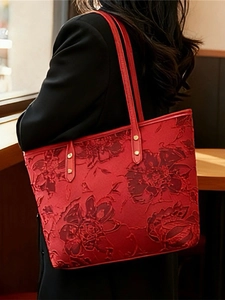 Elegant red tote bag with floral embossing and gold rivets shown on model's shoulder