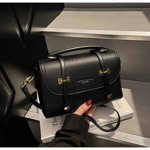 Close-up of black lychee grain leather vintage satchel with elegant gold buckle