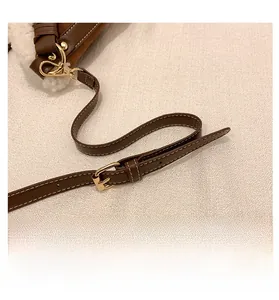 Detail of adjustable brown leather shoulder strap with gold metal buckle on faux fur bag