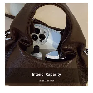 Macro detail of dark brown dumpling bag interior showing capacity for phone and cosmetics