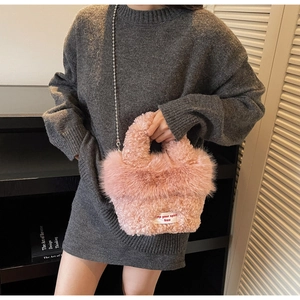 Détail du sac à main en peluche rose avec chaîne de perles porté par un mannequin
