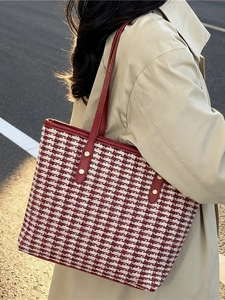 Red and white tweed tote bag for women with leather straps and gold rivets shown outdoors