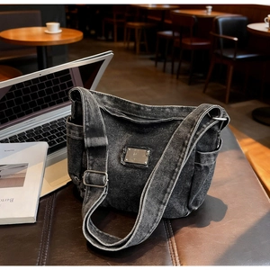 Gros plan d'un sac messager en denim noir vintage avec plaque en métal dans un café