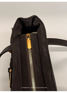 Close-up of retro gold zipper and pebbled leather texture on dark brown handbag