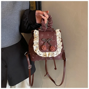 Détail du mini sac à dos vintage avec bordure en dentelle et breloques cerise pour femme