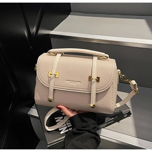 Detailed close-up of beige lychee texture leather with elegant gold metal buckles