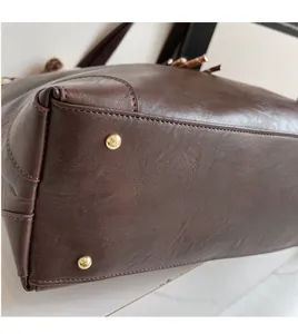 Close-up of brown leather bag base featuring durable gold metal protective studs