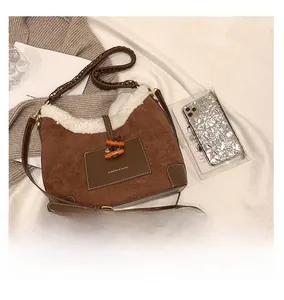 Detail of brown suede crossbody bag featuring white faux fur trim and wooden toggle button