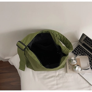 Interior view of green plaid tote bag showing black fabric lining and zippered pocket