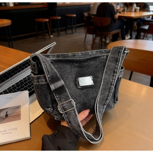 Gros plan détaillé d'un sac bandoulière en denim gris délavé avec boucle en métal ajustable