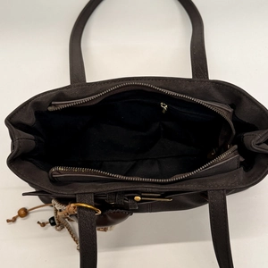 Top view of dark brown tote bag showing zipper closure, black lining, and boho bead charm