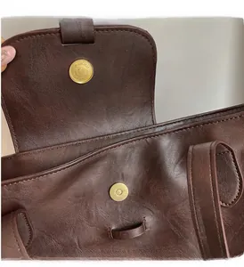 Detail of the golden cylindrical magnetic clasp on a dark brown leather tote bag
