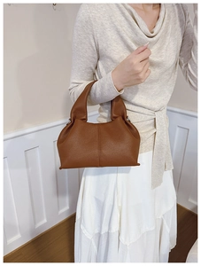 Gros plan d'un sac seau en cuir marron avec texture grainée et design plissé élégant