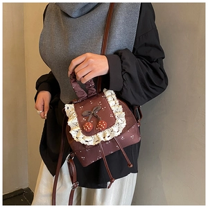 Détail d'un mini sac à dos marron vintage avec bordure en dentelle et fraises