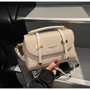 Detail of beige lychee leather crossbody bag with gold hardware and fashion lettering