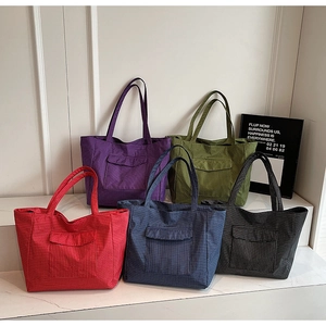 Detail of five plaid tote bags in red, green, blue, purple, and black with front flap pockets