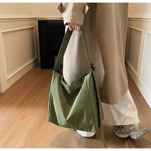 Green plaid canvas tote bag worn by model showing casual style and large capacity