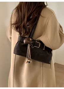 Detail of black matte underarm bag featuring vintage buckle and heart tassel pendant