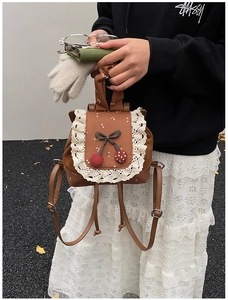 Détail d'un mini sac à dos en cuir marron vintage avec imprimé fleuri et dentelle blanche