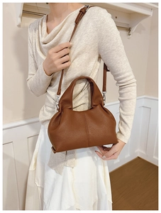 Brown lychee texture bucket bag shown as crossbody with adjustable silver strap