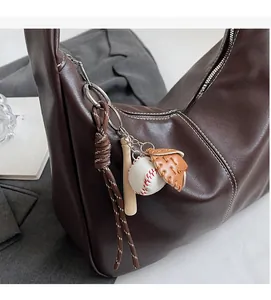 Détail du sac seau en cuir marron foncé avec porte-clés batte de baseball et gant de sport