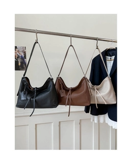 Trois couleurs de grands sacs cabas en cuir tressé suspendus dans un décor studio