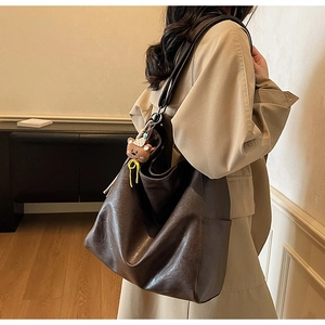 Detail of a brown vintage leather hobo bag featuring a cute plush bear pendant accessory