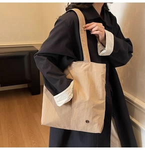 Détail du sac cabas beige en nylon imperméable avec étiquette de marque et bouton pression