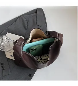 Intérieur spacieux du sac seau marron montrant le rangement tablette, téléphone et portefeuille