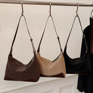 Detailed view of suede shoulder bags in brown, beige, and black with leather base trim