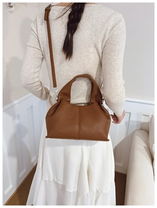 Detailed macro view of caramel brown lychee grain texture and pleats on the cloud handbag