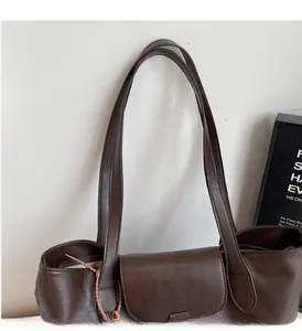 Detail of dark brown tote bag featuring a leather texture, top flap, and pink decorative string