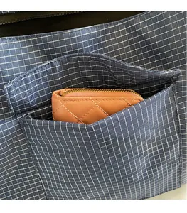 Detail of blue plaid tote bag showing exterior mesh pocket and interior storage capacity
