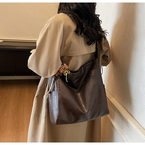 Macro detail of brown soft leather tote bag with woven zipper and plush bear charm