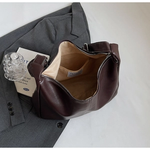 Detail view of large brown tote bag with white stitching and beige fabric lining