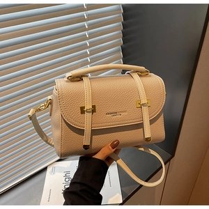 Close-up of beige pebble leather handbag featuring gold buckles and stylish top handle