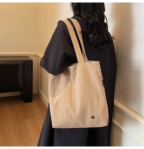 Détail d'un grand sac cabas beige en tissu imperméable avec une large bandoulière confortable
