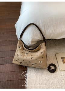 Detail of vintage tan hobo bag featuring silver metal eyelets and detachable strap
