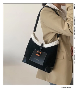 Detail of winter bucket bag featuring black suede, white faux fur trim, and horn buttons