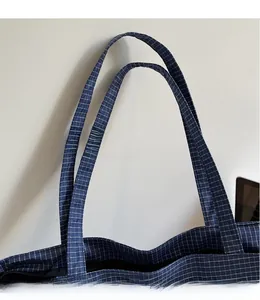 Detail of wide straps and navy plaid woven texture on this large oxford tote bag